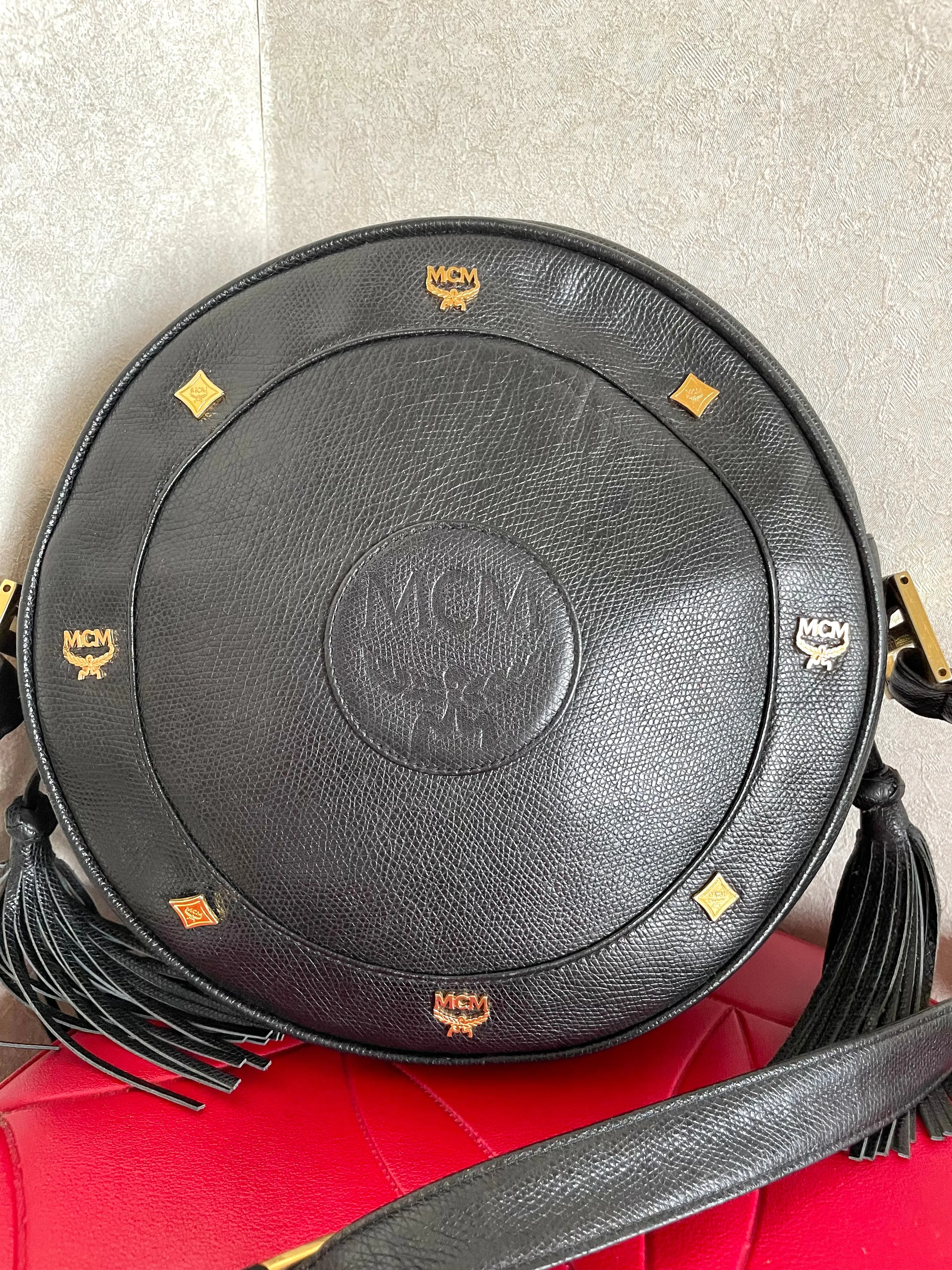 Vintage MCM black suzy wong, grained leather round shoulder bag with golden logo studs and fringes. Designed by Michael Cromer.0407051