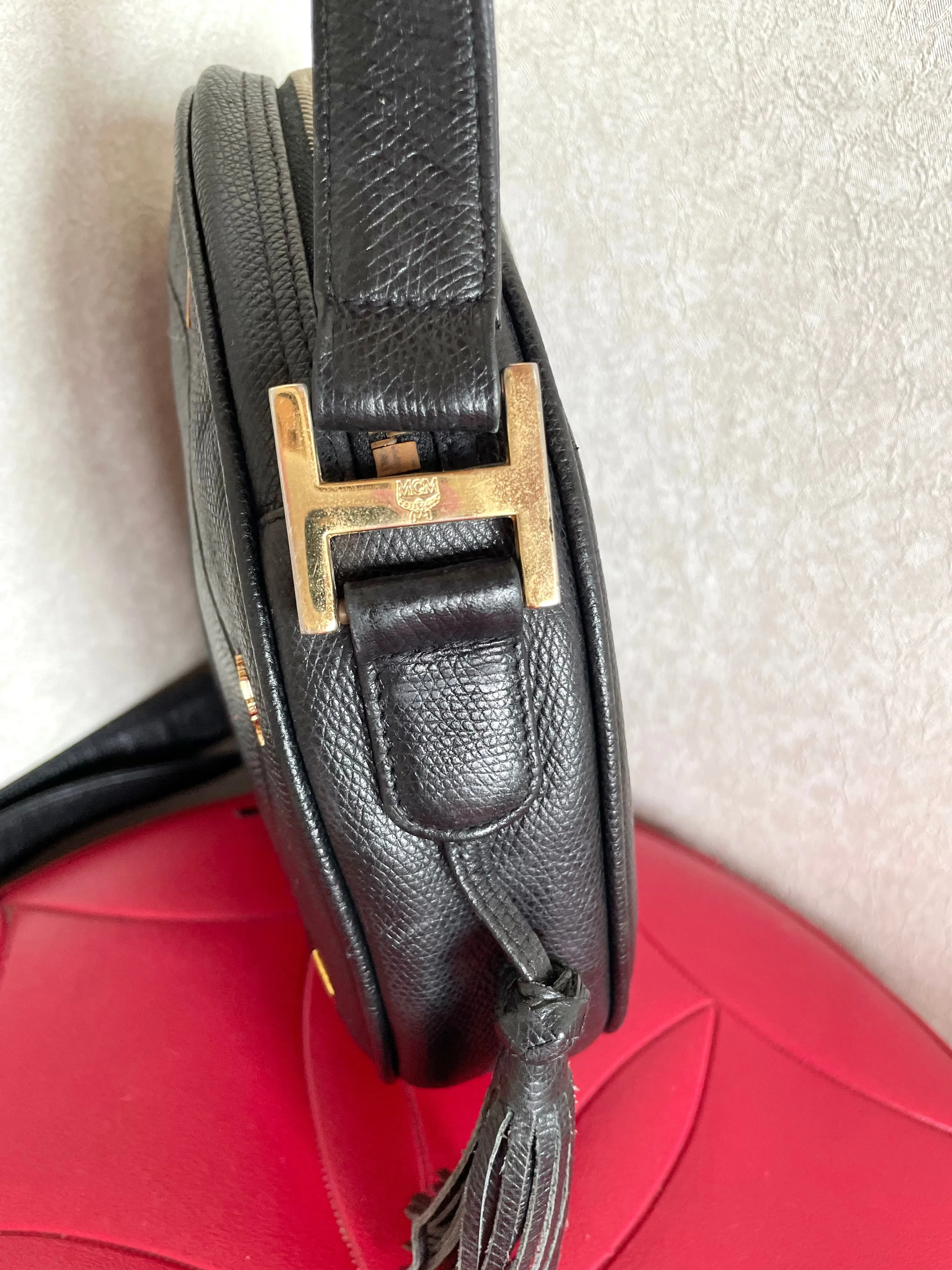 Vintage MCM black suzy wong, grained leather round shoulder bag with golden logo studs and fringes. Designed by Michael Cromer.0407051