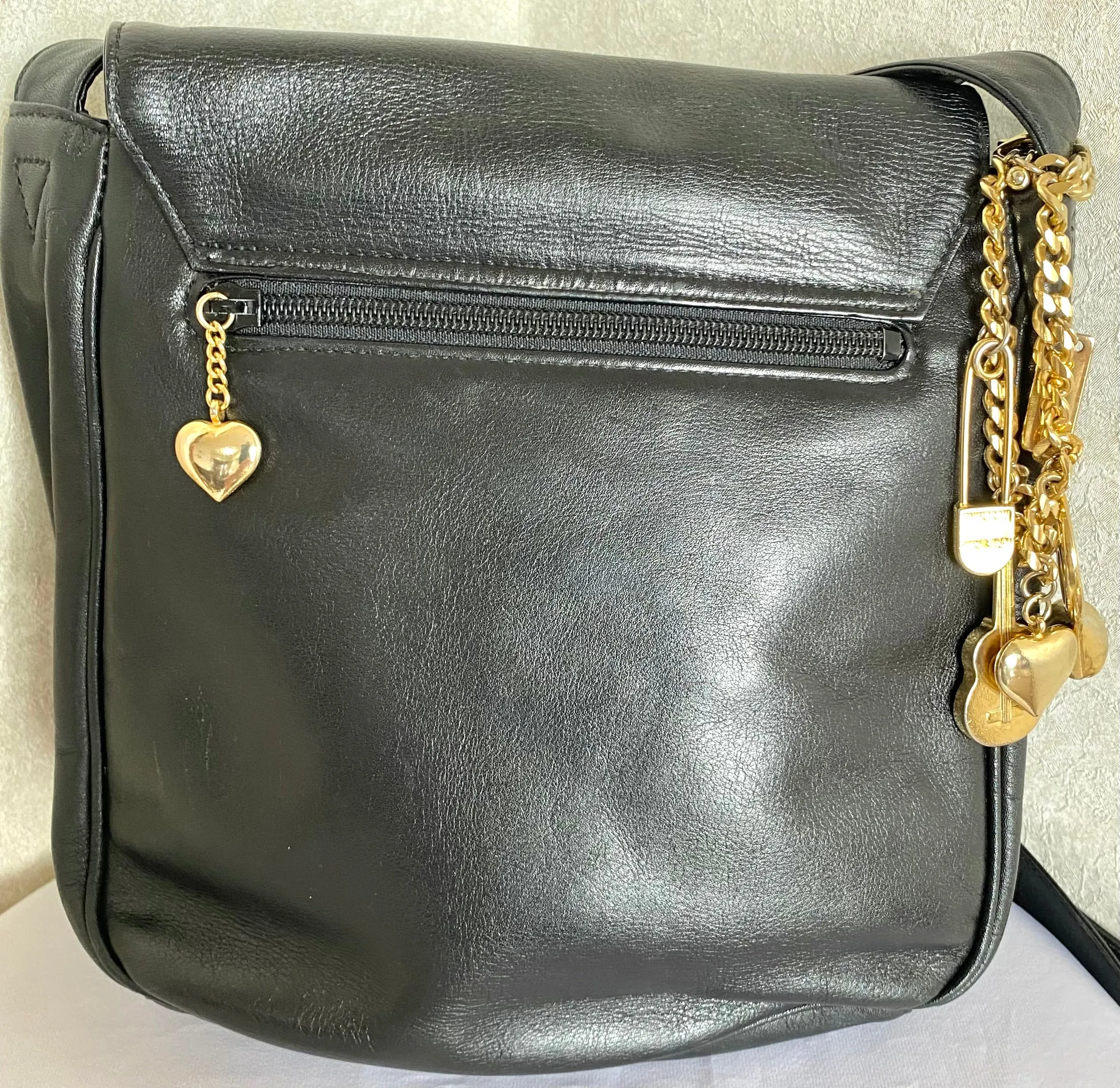Vintage Moschino black leather shoulder bag with golden cute dangling charms. Heart, safety pin, trumpet, sacks, and guitar. 050725
